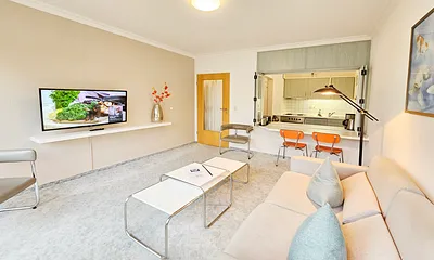 Flat-TV, Couch, Sessel und Blick zur Küche