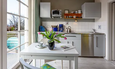 Die Küchenzeile mit Geschirrspüler, Mikrowelle und 2-Platten-Cerankochfeld.