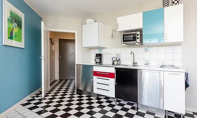 Die Küchenzeile im Wohnzimmer mit Geschirrspüler und Mikrowelle.