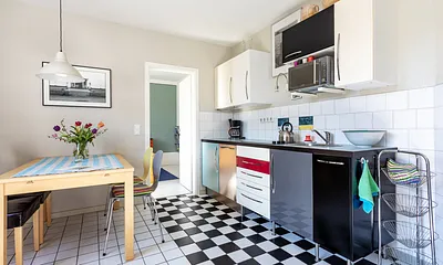 Die Küchenzeile im Wohnzimmer mit Geschirrspüler und Mikrowelle.