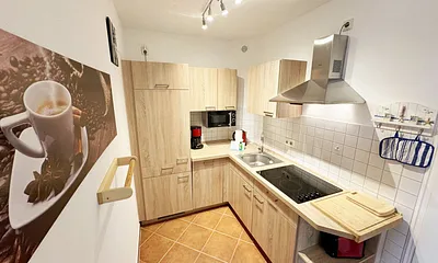 Küchenzeile mit Geschirrspüler, Cerankochfeld, Kühlschrank mit Eisfach, Mikrowelle, Kaffeemaschine, Wasserkocher und ein Toaster