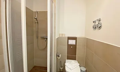 Badezimmer mit ebenerdiger Dusche, Waschtisch, WC, Handtuchtrockner und Fön