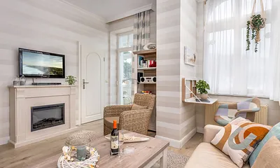 Der elektrische Kamin mit HiFi-Anlage, kleinem Schreibtisch und TV. Im Hintergrund der Durchgang zur geschlossenen Loggia nach Süden.