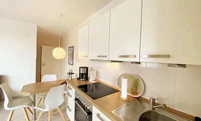 offene Küchenzeile mit Backofen, Cerankochfeld, Kühlschrank mit Gefrierfach, Geschirrspüler, Kaffeemaschine, Toaster sowie ein Wasserkocher