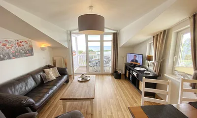 Wohnbereich mit bequemer Ledercouch, Lesesessel mit Hocker, Couchtisch, TV-Board mit Flachbild-TV, Musikanlage und Urlaubslektüre 