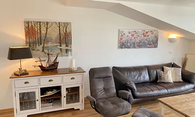 Wohnbereich mit bequemer Ledercouch, Lesesessel mit Hocker, Couchtisch, TV-Board mit Flachbild-TV, Musikanlage und Urlaubslektüre 