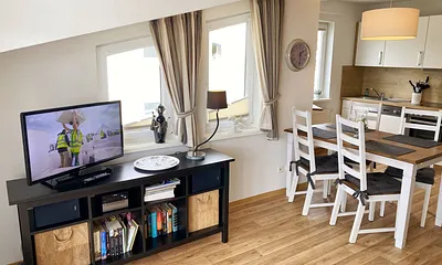 Wohnbereich mit bequemer Ledercouch, Lesesessel mit Hocker, Couchtisch, TV-Board mit Flachbild-TV, Musikanlage und Urlaubslektüre 