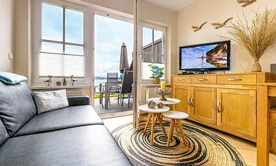 komfortabler Wohnbereich mit Couch, Couchtisch, Sessel, Stehlampe, Kommode mit Flachbild-TV