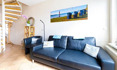 komfortabler Wohnbereich mit Couch, Couchtisch, Sessel, Stehlampe, Kommode mit Flachbild-TV