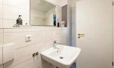 Badezimmer mit Dusche, WC, Fön sowie ein Waschplatz mit dazugehörigem Spiegel