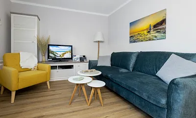 komfortabler Wohnbereich mit Schlafcouch (Aufbettungsmöglichkeit 1,40 m x 1,90 m), Couchtisch, Sessel, Stehlampe sowie eine Kommode mit Flachbild-TV