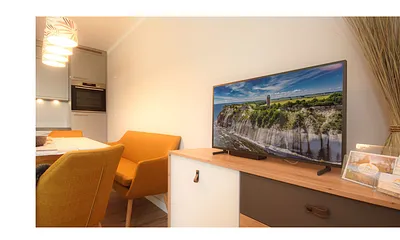 komfortabler Wohnbereich mit Couch (Aufbettungsmöglichkeit 1,40m x 1,90m), Couchtisch, Sessel, Stehlampe sowie einer Kommode mit Flachbild-TV