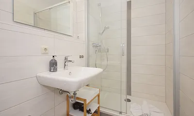 innenliegendes Badezimmer mit Dusche, WC, Fön sowie ein Waschplatz mit dazugehörigem Spiegel