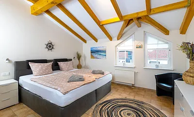 Schlafzimmer mit Boxspringbett (2,00 m x 2,00 m), Nachttischablage, Kleiderschrank, Kommode sowie ein Sessel