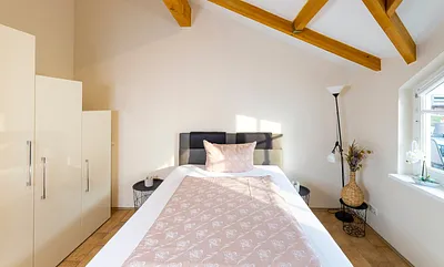 Schlafzimmer mit Boxspringbett (1,40 m x 2,00 m), Nachttischablage, Kleiderschrank, Kommode, Stehlampe sowie ein Standspiegel