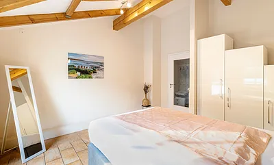 Schlafzimmer mit Boxspringbett (1,60 m x 2,00 m), Nachttischablage, Kleiderschrank, Kommode, Stehlampe sowie ein Standspiegel