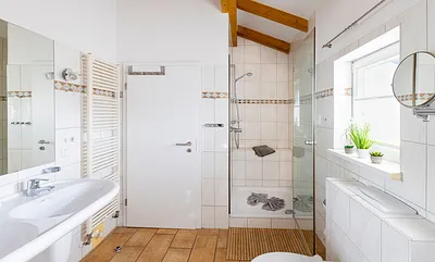 Badezimmer mit geräumiger Eck-Badewanne, WC, Fön, Kosmetikspiegel und ein Doppelwaschplatz mit dazugehörigem Spiegel