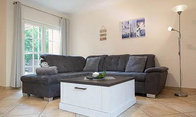 Der Wohnbereich mit gemütlicher Couchgarnitur und Zugang zur möblierten Terrasse