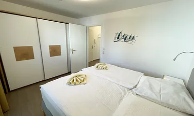 Schlafzimmer mit bequemem Boxspringbett (1,80 m x 2,00 m), Nachttischablagen, geräumiger Kleiderschrank und Verdunkelungsvorhängen