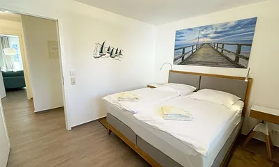 Schlafzimmer mit bequemem Boxspringbett (1,80 m x 2,00 m), Nachttischablagen, geräumiger Kleiderschrank und Verdunkelungsvorhängen