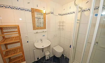 Badezimmer mit flacher Dusche, Waschplatz, WC, Fön, Kosmetikspiegel und Handtuchheizkörper
