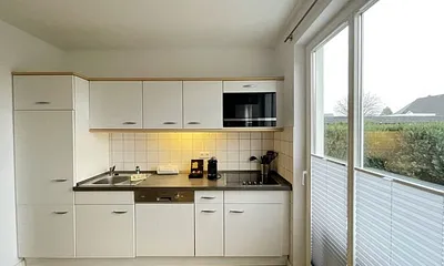 moderne Einbauküche mit Induktionsherd, Kühlschrank mit Gefrierfach, Mikrowelle, Geschirrspüler, Filter-Kaffeemaschine, Nespresso-Kapselmaschine, Wasserkocher, Toaster und Messerblock 