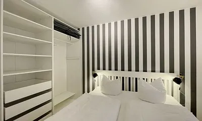 Schlafzimmer mit Doppelbett (1,80 m x 2,00 m), Wand-Nachttischlampe, verstellbare Lattenroste, Insektenschutzgitter sowie ein geräumiger und offener Kleiderschrank