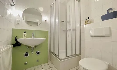 innenliegendes Badezimmer mit Eck-Dusche, Fön, WC, Ablage, beleuchteter Spiegel, Insektenschutzgitter und ein Waschplatz