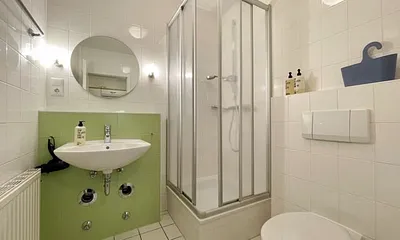 innenliegendes Badezimmer mit Eck-Dusche, Fön, WC, Ablage, beleuchteter Spiegel, Insektenschutzgitter und ein Waschplatz