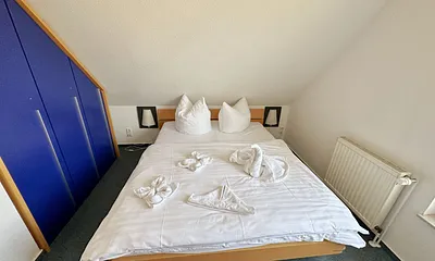 Schlafzimmer mit Doppelbett (1,60 m x 2,00 m), Wand-Nachttischlampe, verstellbare Lattenroste sowie ein geräumiger Kleiderschrank