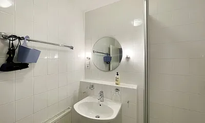 innenliegendes Badezimmer mit Eck-Dusche, Fön, WC, Ablage, beleuchteter Spiegel, Insektenschutzgitter und ein Waschplatz