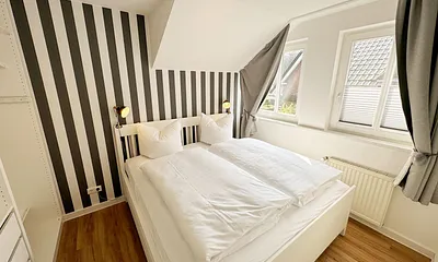 Schlafzimmer mit Doppelbett (1,60 m x 2,00 m), Wand-Nachttischlampe, verstellbare Lattenroste sowie ein geräumiger Kleiderschrank
