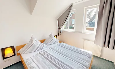 Schlafzimmer mit Doppelbett (1,60 m x 2,00 m), Wand-Nachttischlampe, verstellbare Lattenroste sowie ein geräumiger Kleiderschrank