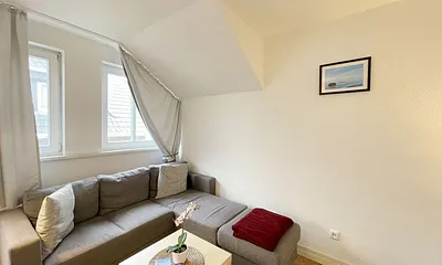 Wohnzimmer mit bequemer Eckcouch, Couchtisch, Stehlampe, 32-Zoll-Smart-TV, Bluetooth-Radio, Sideboard sowie eine Spielesammlung und kleine Auswahl an Büchern