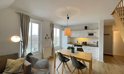 Wohnbereich mit bequemer Eckcouch, Couchtisch, Sessel, Stehlampe, 55-Zoll-Smart-TV, Bluetooth-Radio, Sideboard sowie eine Spielesammlung und kleine Auswahl an Büchern