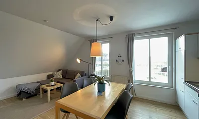 Wohnbereich mit bequemer Eckcouch, Couchtisch, Sessel, Stehlampe, 55-Zoll-Smart-TV, Bluetooth-Radio, Sideboard sowie eine Spielesammlung und kleine Auswahl an Büchern
