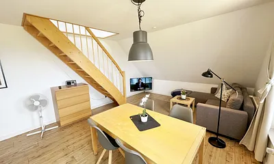 Wohnbereich mit bequemer Eckcouch, Couchtisch, Sessel, Stehlampe, 55-Zoll-Smart-TV, Bluetooth-Radio, Sideboard sowie eine Spielesammlung und kleine Auswahl an Büchern