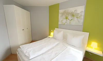 Schlafzimmer mit Doppelbett (1,60 m x 2,00 m), hochwertigen Matratzen, verstellbaren Lattenrosten, 2 Nachttischlampen, Flachbild-TV, Radiowecker und Kleiderschrank