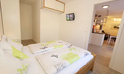 Schlafzimmer mit Doppelbett (1,80 m x 2,00 m), verstellbare Lattenroste, Nachttischkonsolen, Kleiderschrank und einem Flachbild-TV