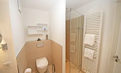 Badezimmer mit bodentiefer Echtglasdusche, Kosmetikspiegel, Fön, Handtuchtrockner sowie einer Lichtkuppel, die diesen Raum schon ab dem frühen Morgen erhellt