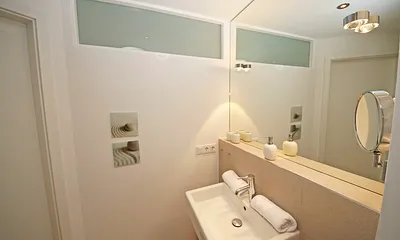 Badezimmer mit bodentiefer Echtglasdusche, Kosmetikspiegel, Fön, Handtuchtrockner sowie einer Lichtkuppel, die diesen Raum schon ab dem frühen Morgen erhellt