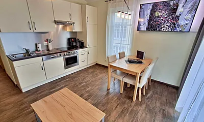 Wohn- und Essbereich mit gemütlicher Couch, Esstisch, Küchenzeile und Zugang zum Balkom