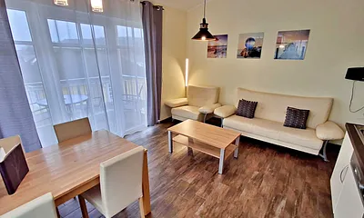 Wohn- und Essbereich mit gemütlicher Couch, Esstisch, Küchenzeile und Zugang zum Balkom