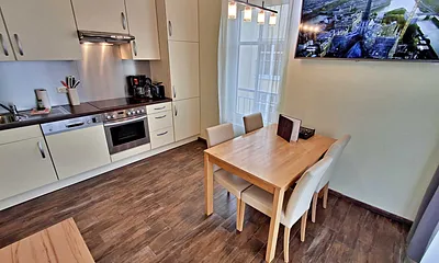 Wohn- und Essbereich mit gemütlicher Couch, Esstisch, Küchenzeile und Zugang zum Balkom