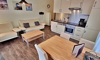 Wohn- und Essbereich mit gemütlicher Couch, Esstisch, Küchenzeile und Zugang zum Balkom