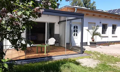 Eingang zum Bungalow und Veranda mit Schiebefenstern