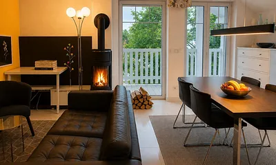 Wohnzimmer mit Kamin und Essbereich und Zugang zu zwei Balkonen.