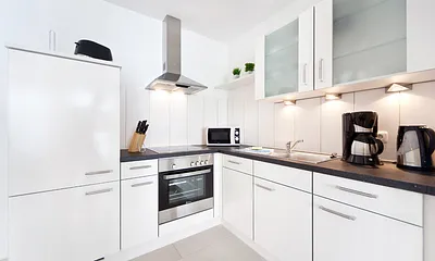 Die moderne Küchenzeile mit Geschirrspüler und Backofen im Wohnzimmer.