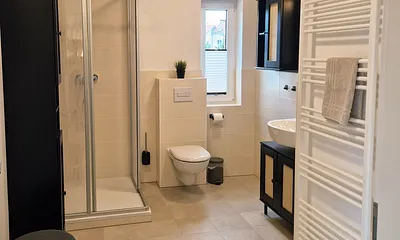 Bad mit begehbarer Dusche, WC, Waschtisch.