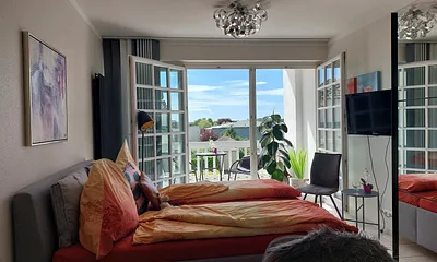 Der schöne Wohnschlafraum hat eine große Fensterfront zum Balkon. TV und kostenfreies WLAn sind vorhanden.